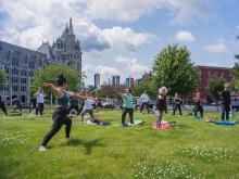 A woman leads a yoga class on a grassy field in front of the SUNY Admin building in downtown Albany, NY